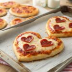 four heart shaped pizzas sitting on top of a pan